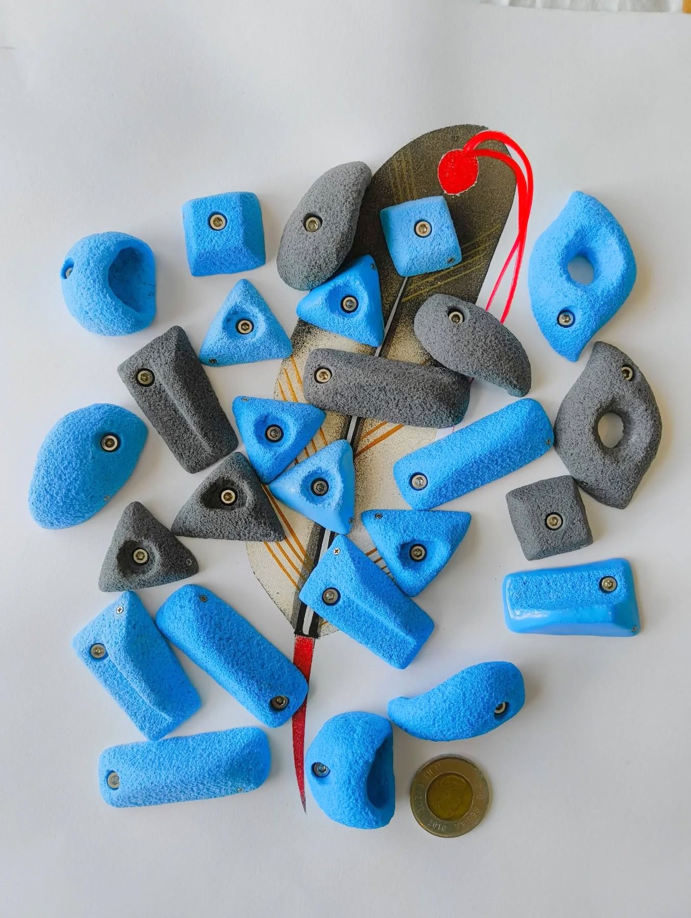 Blue and grey miniature climbing holds arranged around a climbing brush